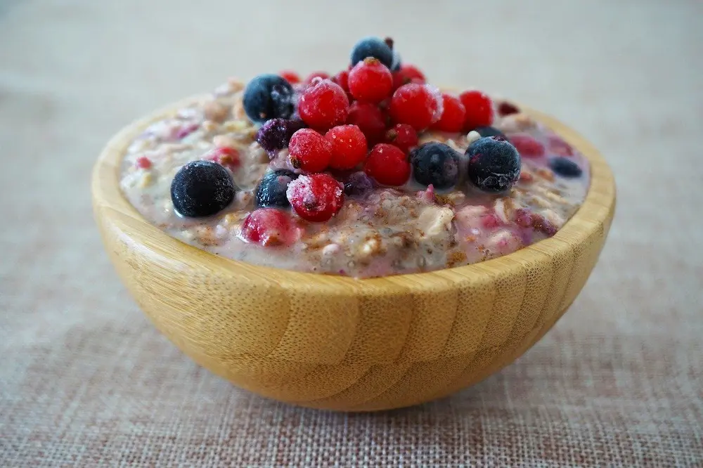 A bowl of porridge with outs and berries on top