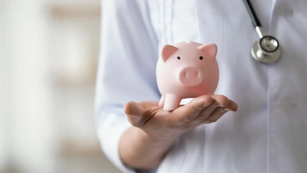 A doctor holding a piggy bank