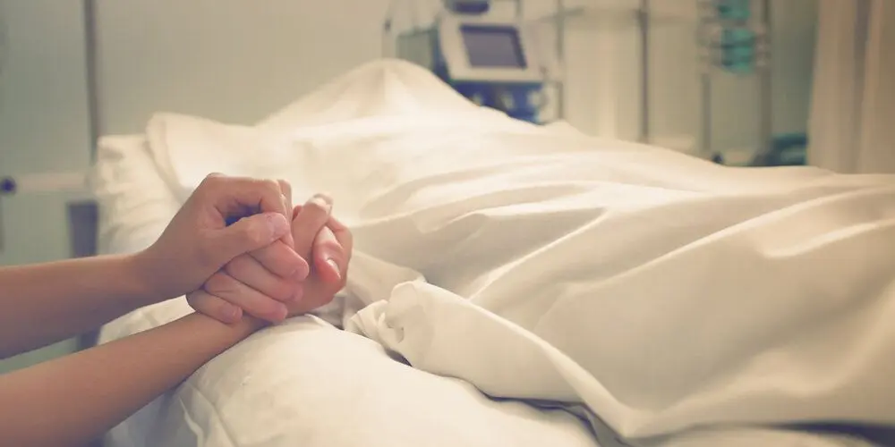 A person holding a dying loved one's hand