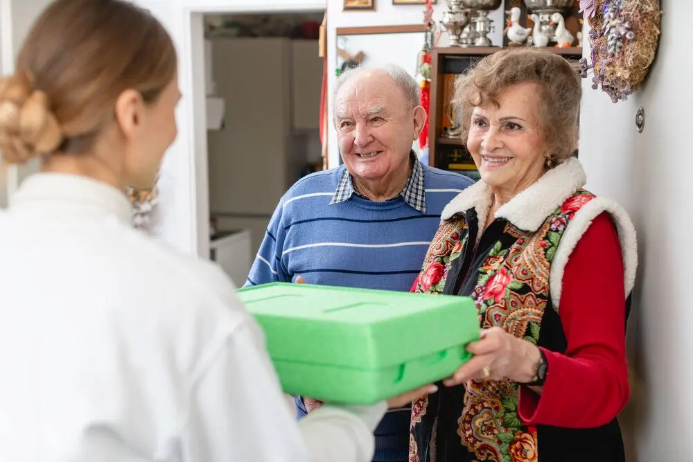 An elderly couple receiving a food delivey at home