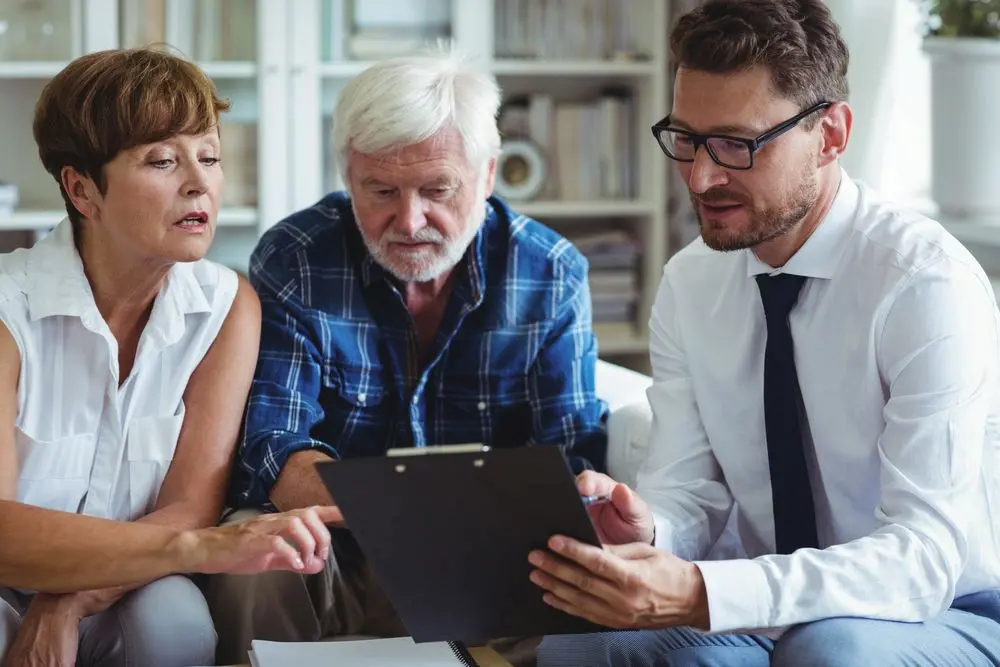 Elderly couple and younger man looking at a clipboard