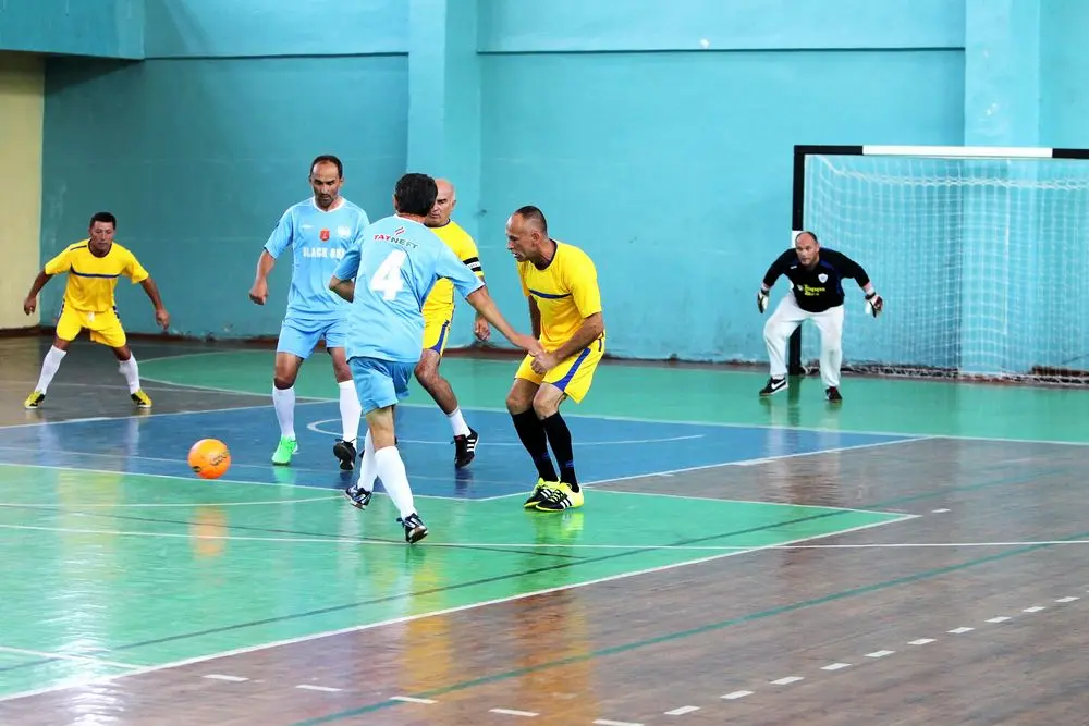 Group of older men playing football indoors