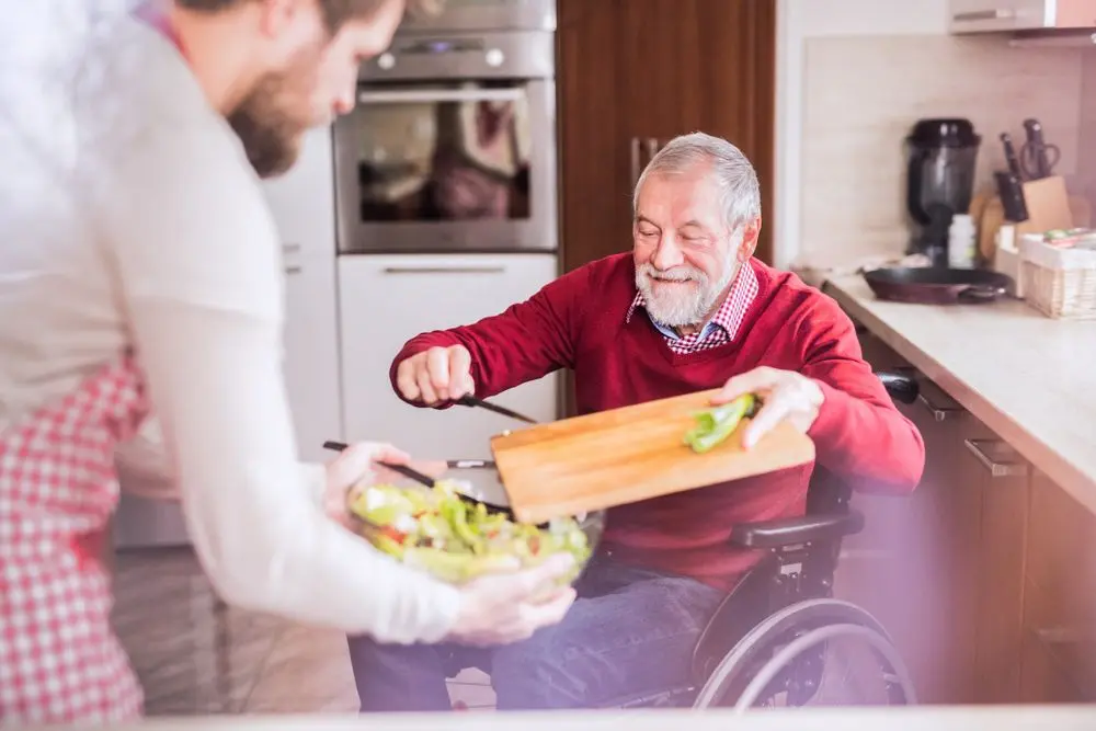 Man in a wheelchair getting help with cooking