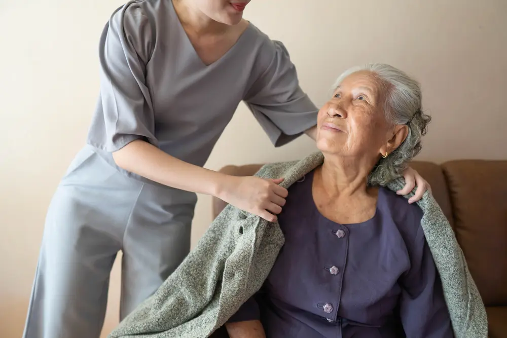 Nurse putting a blanket over an older woman