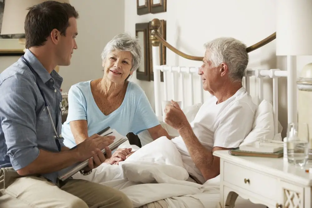 Older couple speaking to a carer in their bedroom