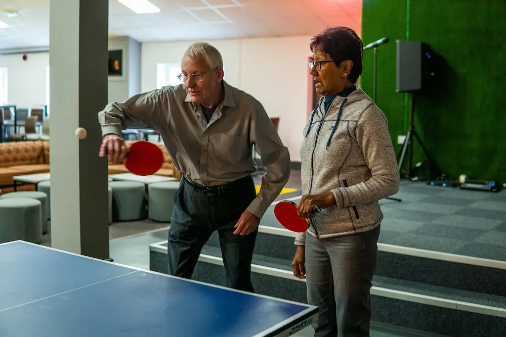 Older man and woman playing table tennis