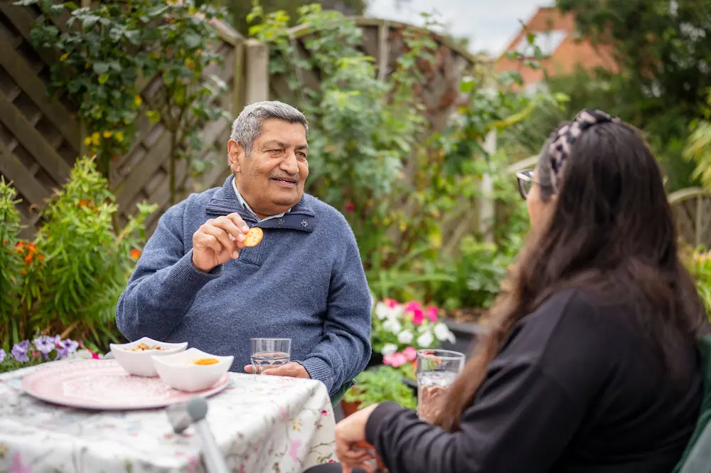 Older man eating biscuits with a younger advocate