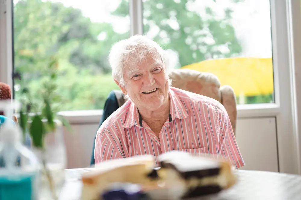 Older man smiling at a table