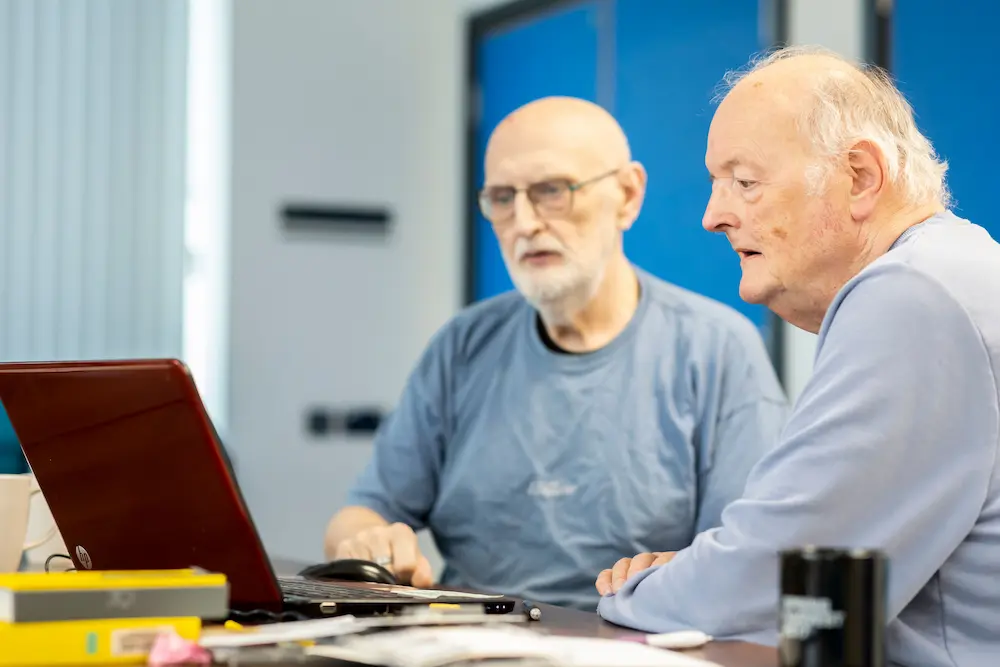 Two older men using a laptop together
