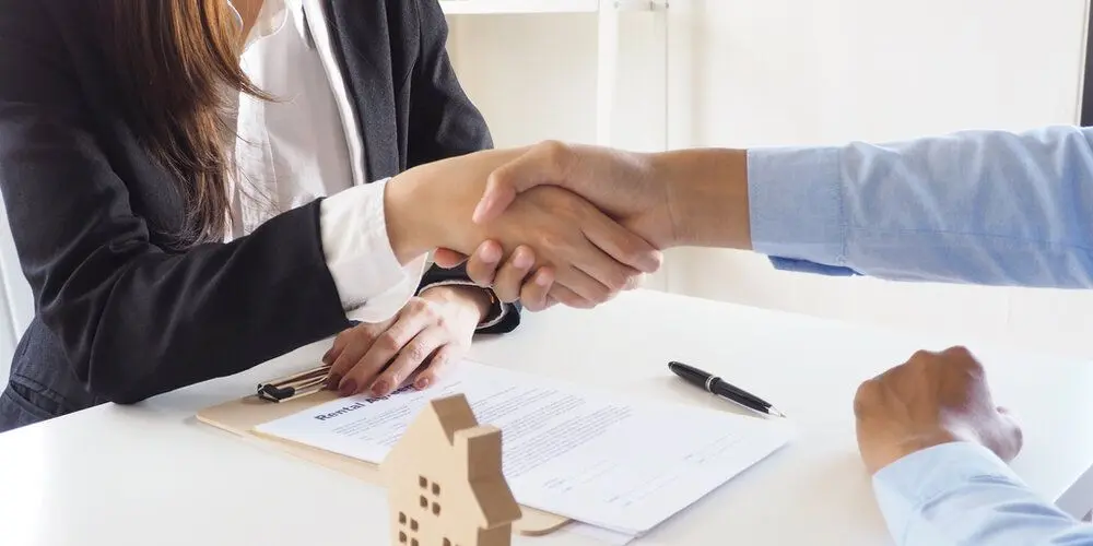 Two people shaking hands after signing a document