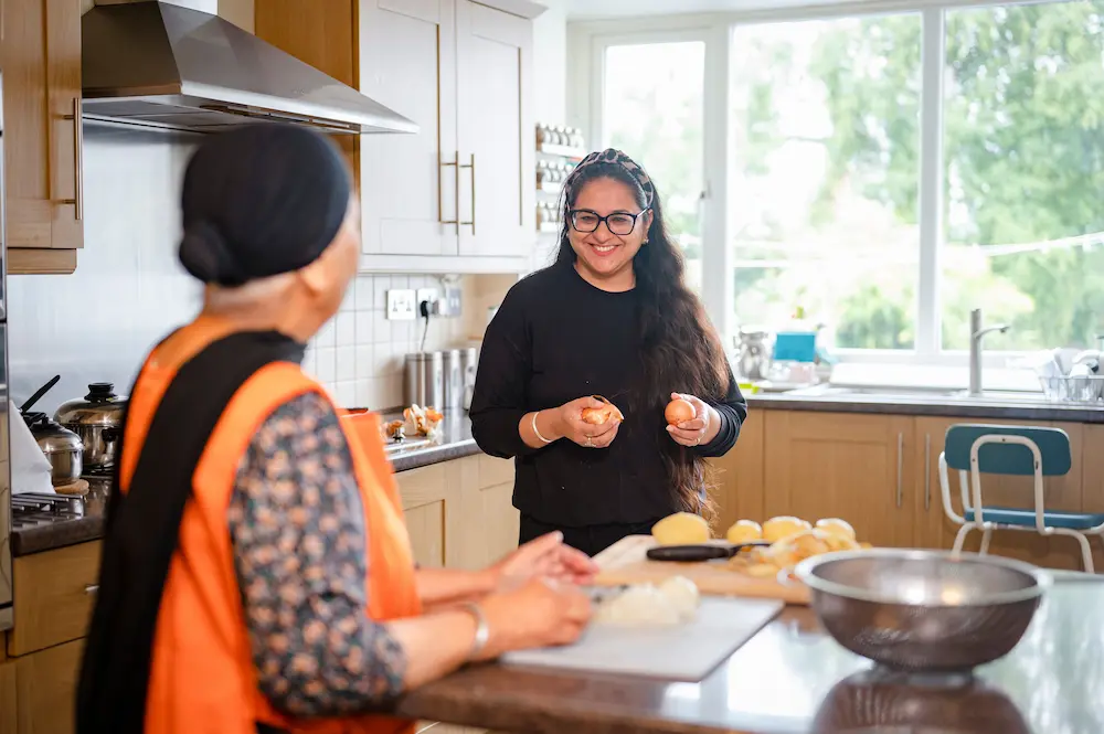 Young female carer preparing food with an older woman